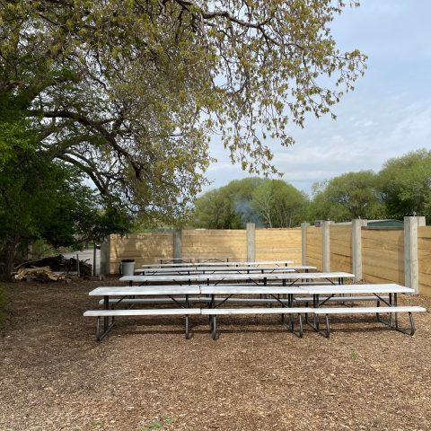 an empty park bench next to a fence