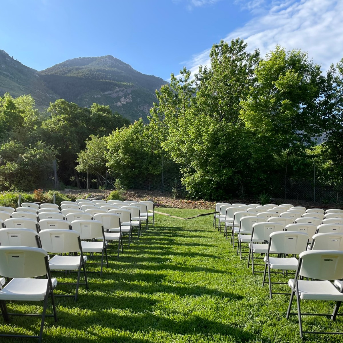 a row of lawn chairs sitting on top of a grass covered field