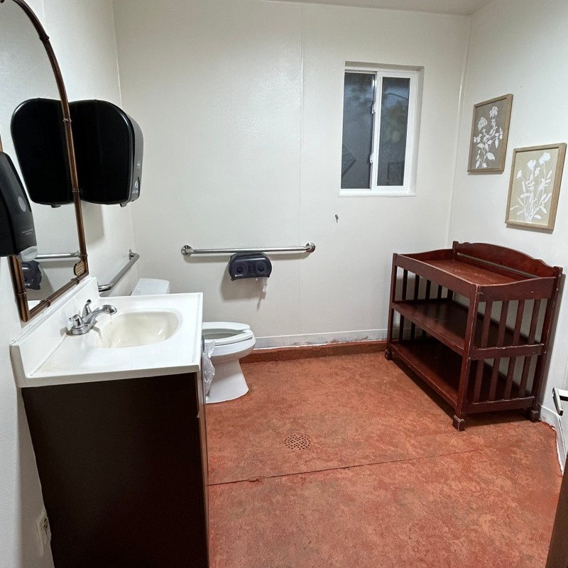 Bathroom with sink, toilet, changing table, and wall mirror.