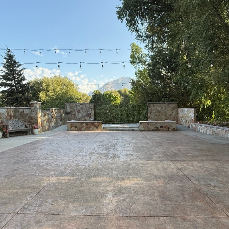 Outdoor courtyard with string lights and two wooden structures on a sunny day.