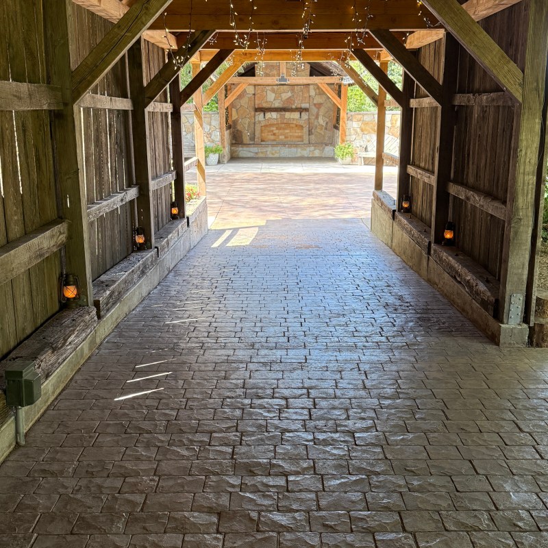 Wooden pavilion with string lights, stone pathway and background fireplace.