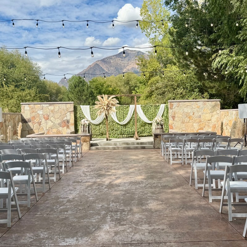 Outdoor wedding setup with chairs and greenery, mountain in background.