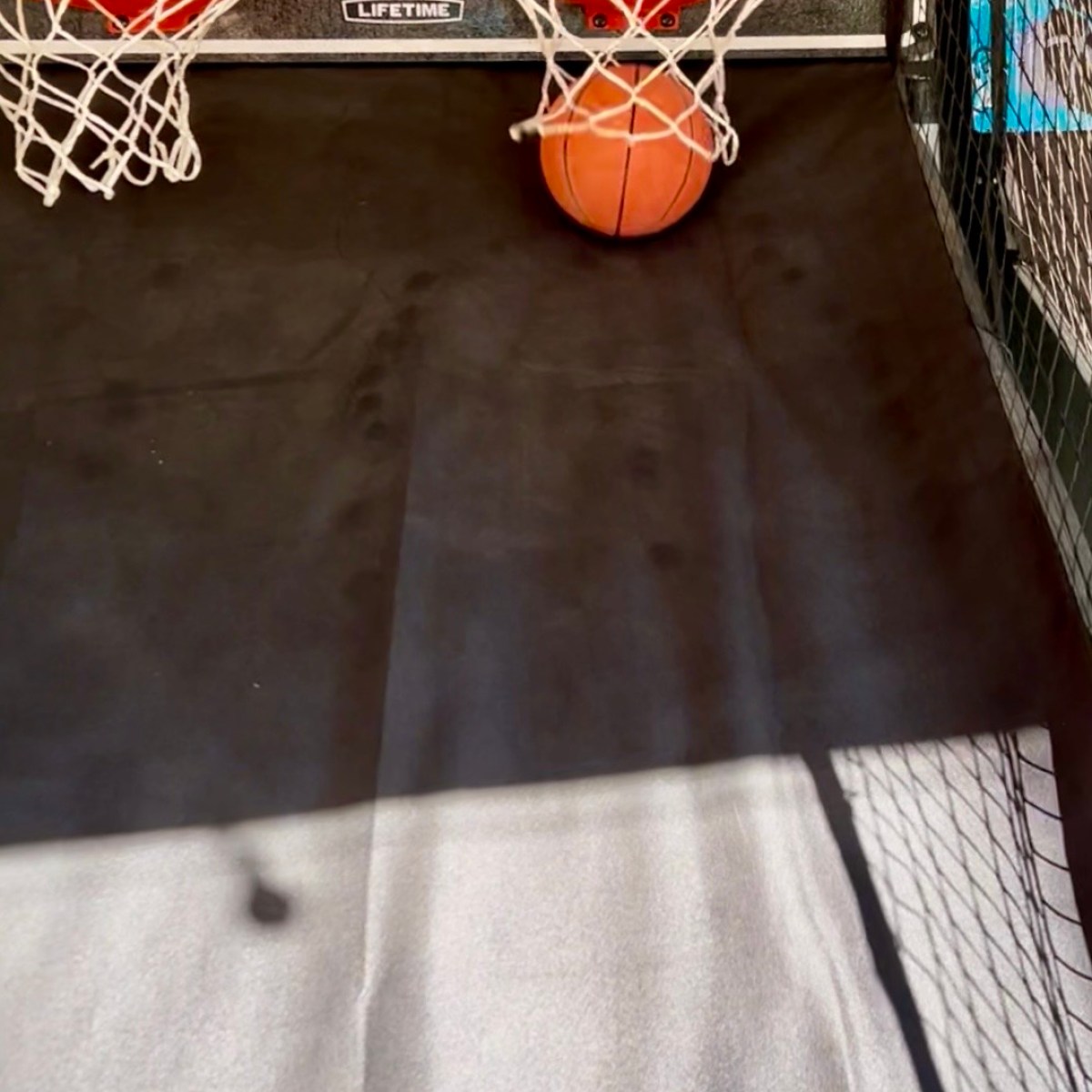 Basketball arcade game with a ball stuck between two hoops.