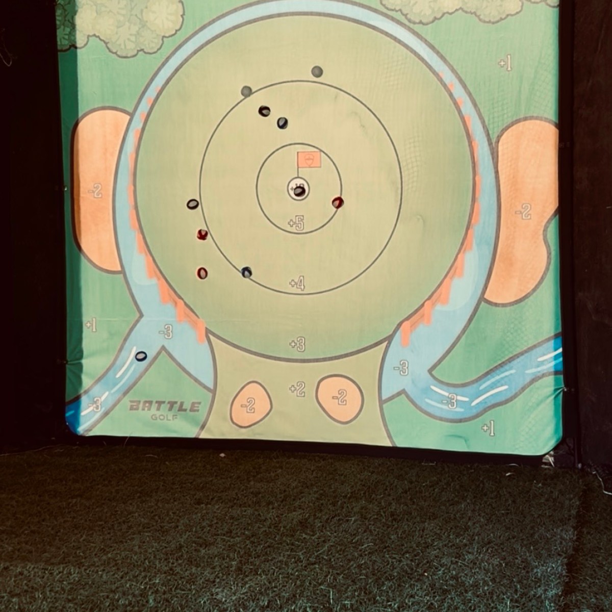 Archery target with various arrows on a grassy surface.