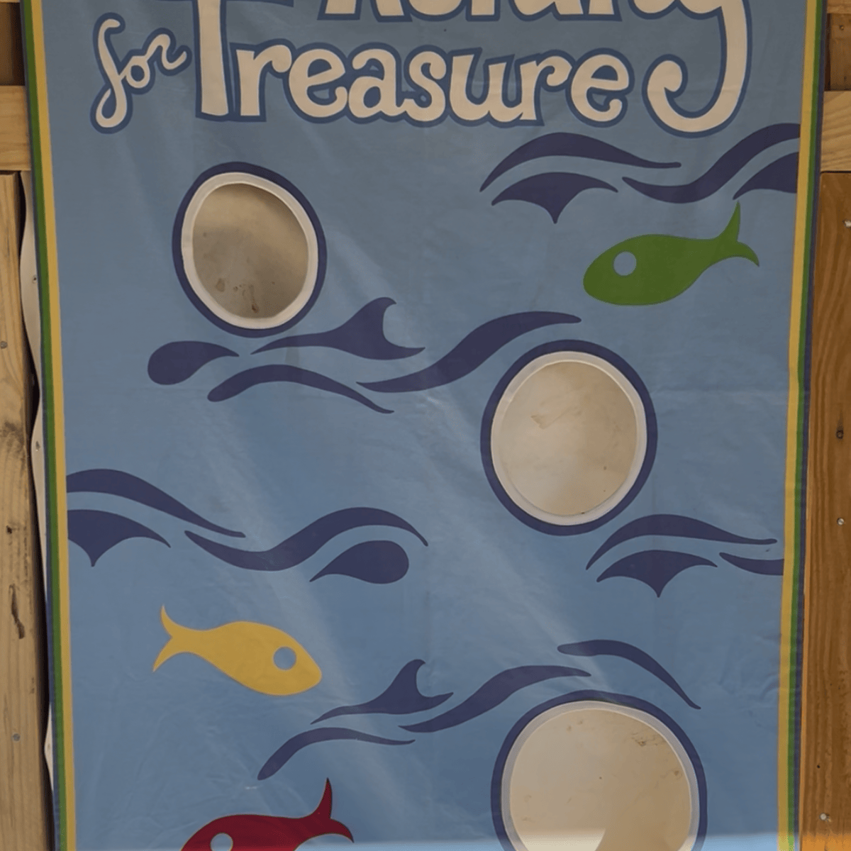 Fishing game banner with fish and target holes.
